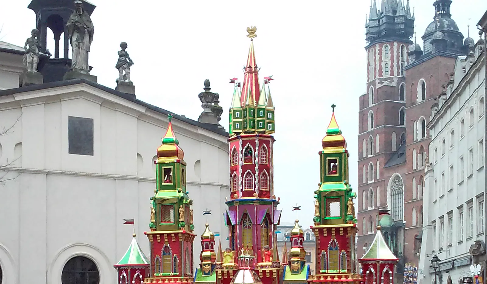Towers of a colourful Kraków szopka with St Mary's Basilica in the background
