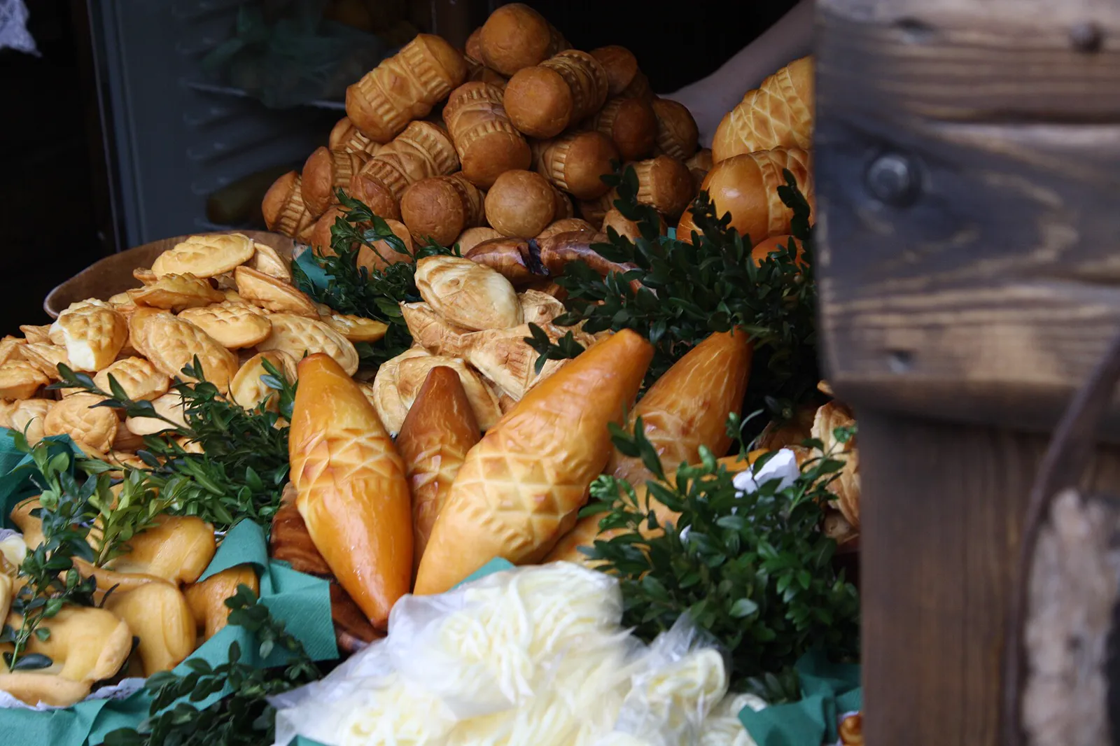 Smoked highland cheeses in different shapes on a stall, with spindle-shaped oscypki in front