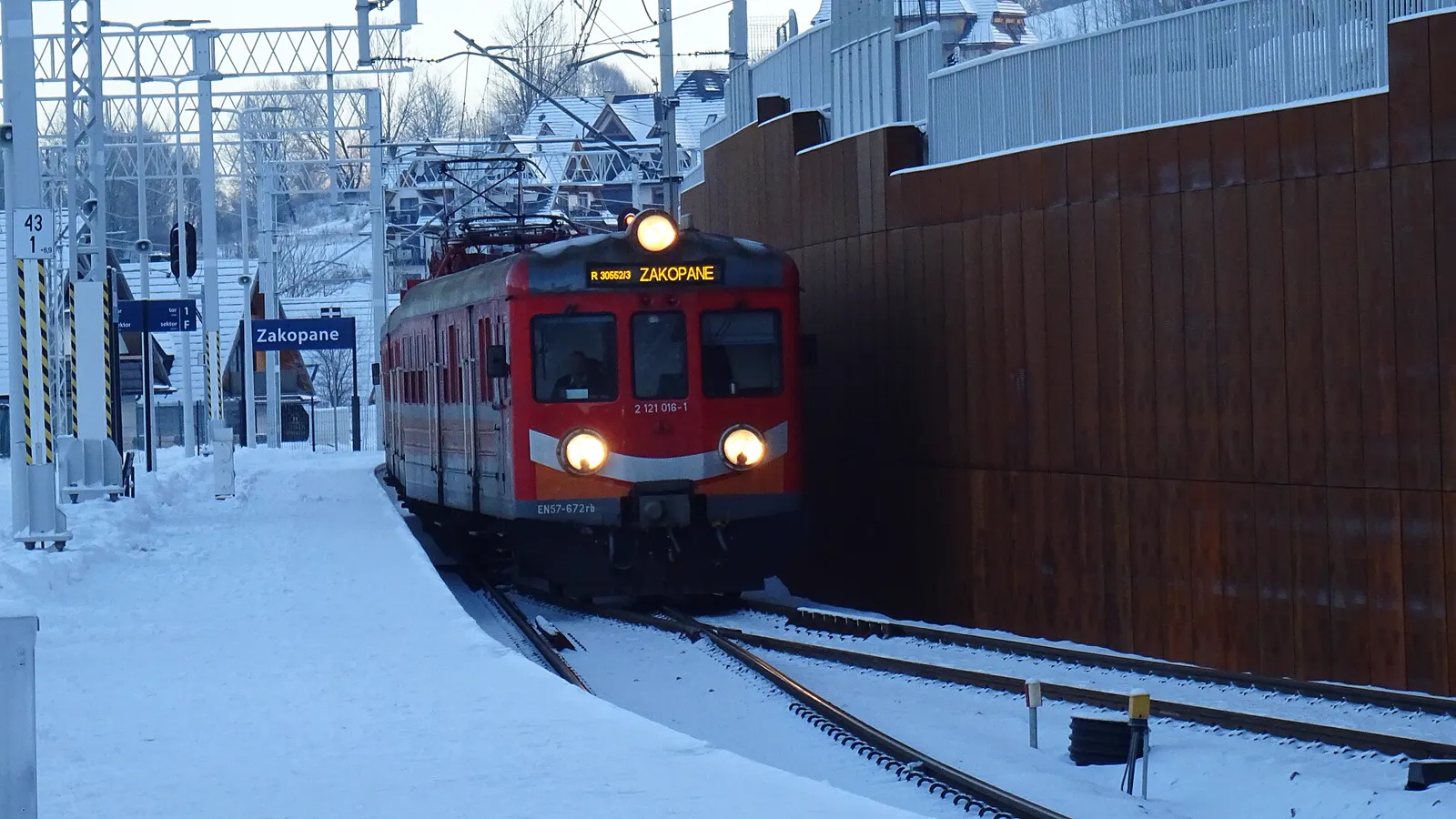 Red regional train with a Zakopane destination board arriving at a snow-covered station