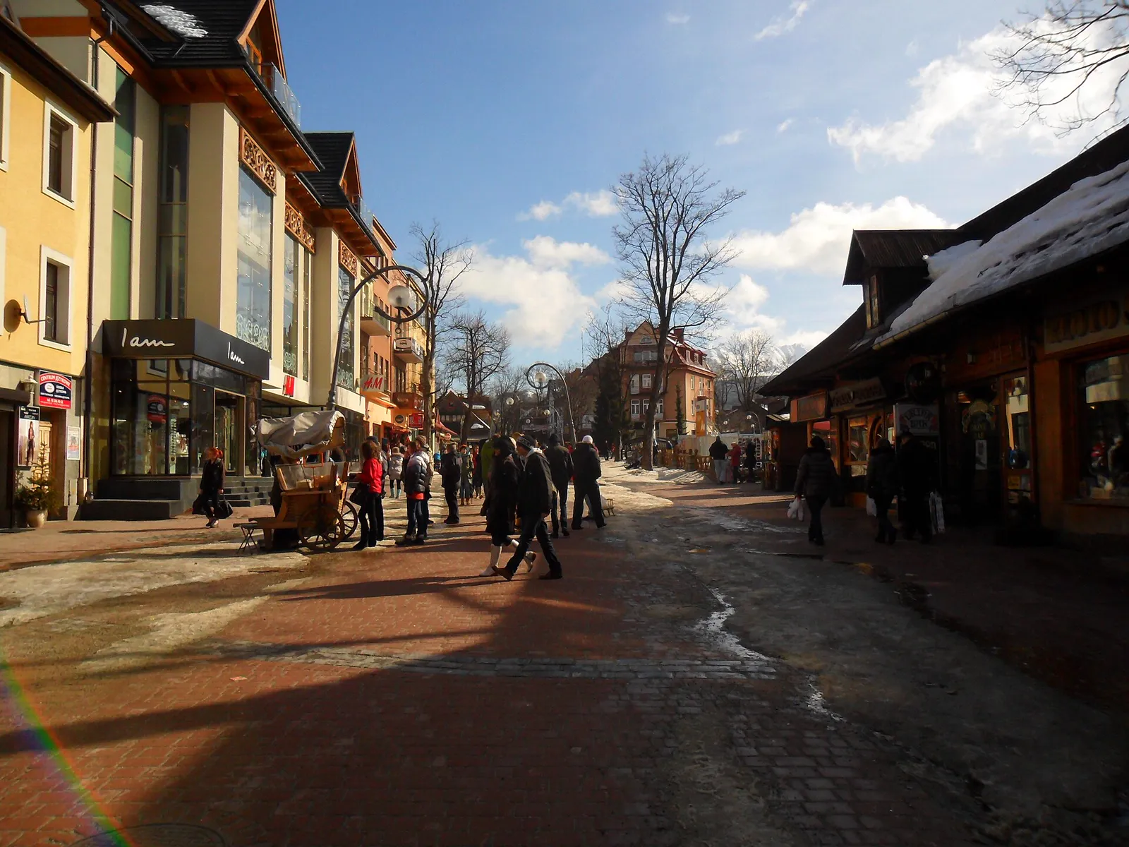 Krupówki street in winter with wooden buildings, snow on the roofs and people walking